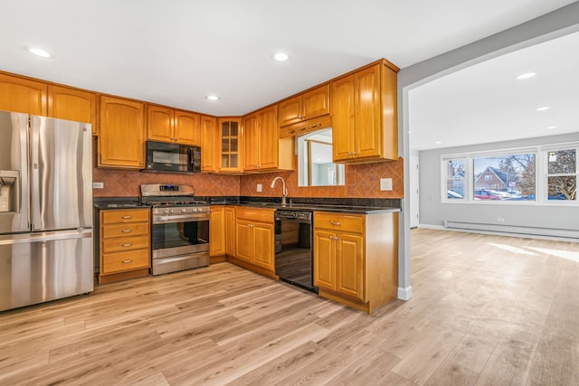 kitchen featuring a baseboard heating unit, dark countertops, light wood-style floors, and black appliances