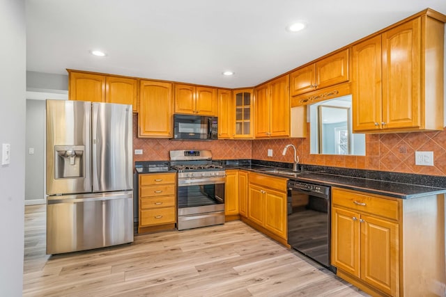 kitchen featuring black appliances, light wood-style flooring, glass insert cabinets, and brown cabinetry