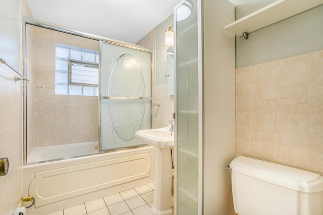 full bath with toilet, combined bath / shower with glass door, tile walls, and tile patterned floors