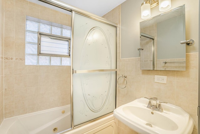 bathroom with shower / bath combination with glass door, tile walls, and a sink