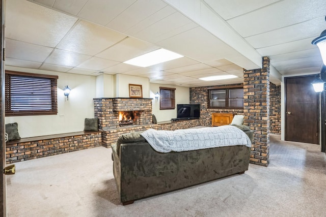 living room featuring carpet floors, a brick fireplace, brick wall, and a drop ceiling