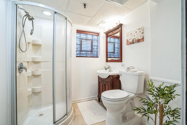 bathroom featuring a paneled ceiling, toilet, a stall shower, vanity, and baseboards