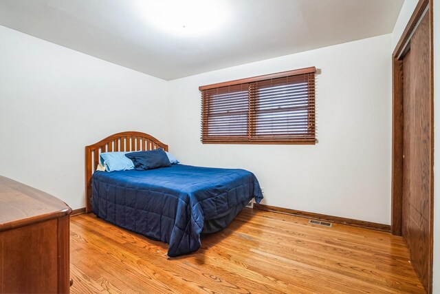 bedroom featuring baseboards, visible vents, and light wood finished floors