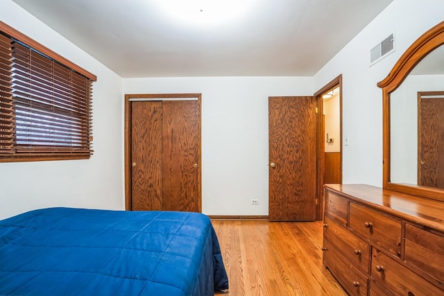 bedroom featuring a closet, light wood-type flooring, visible vents, and baseboards