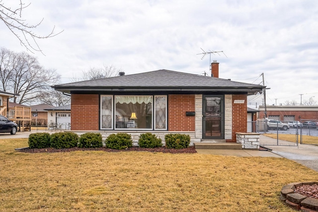 back of house featuring roof with shingles, brick siding, a lawn, and a chimney