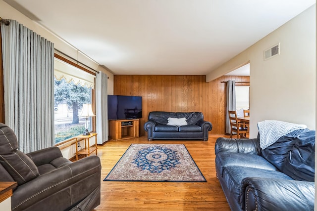 living area with wood walls, wood finished floors, and visible vents