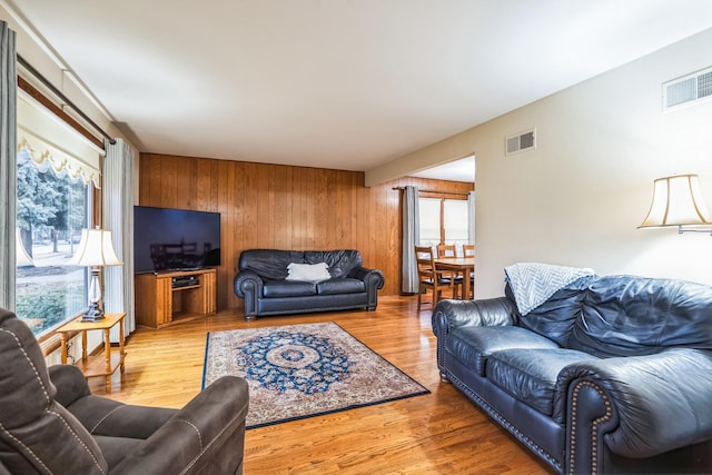 living room featuring wood walls, wood finished floors, and visible vents