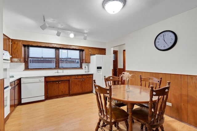 dining space with a wainscoted wall, wooden walls, and light wood-style floors