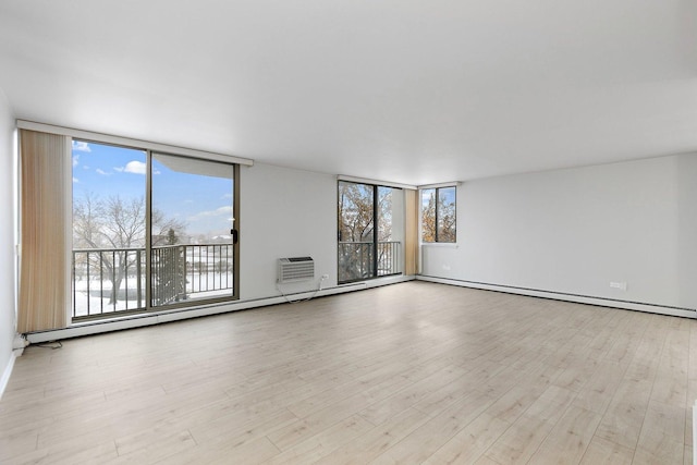 unfurnished room with a wall of windows, wood finished floors, and a wall mounted AC