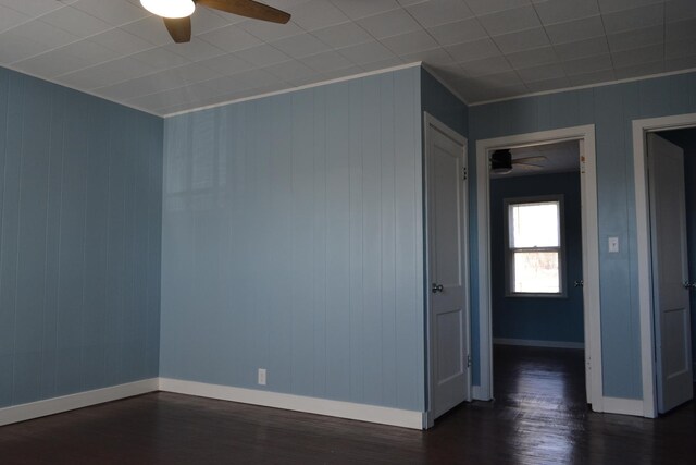 empty room featuring ceiling fan, dark wood-style floors, visible vents, and baseboards