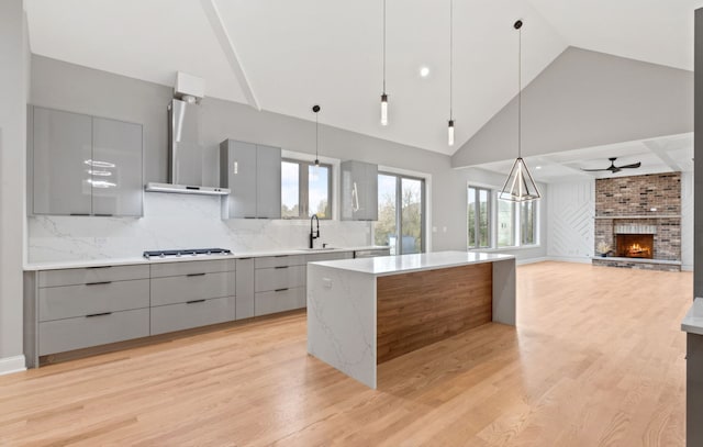 kitchen featuring modern cabinets, gray cabinets, wall chimney range hood, gas cooktop, and a sink