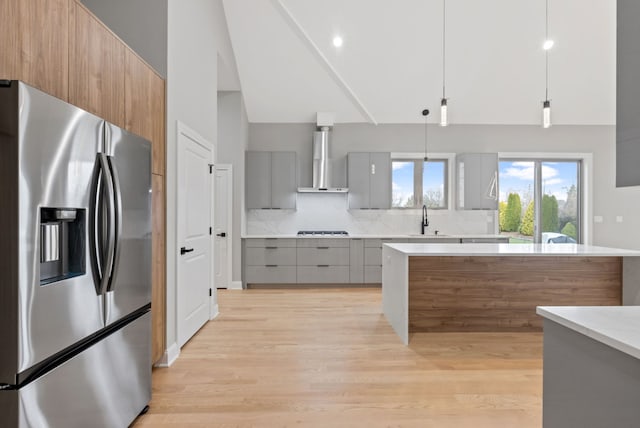 kitchen featuring stainless steel fridge, a sink, wall chimney exhaust hood, and modern cabinets