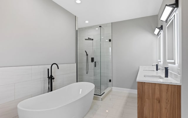 bathroom with recessed lighting, vanity, tile walls, a freestanding bath, and a shower stall