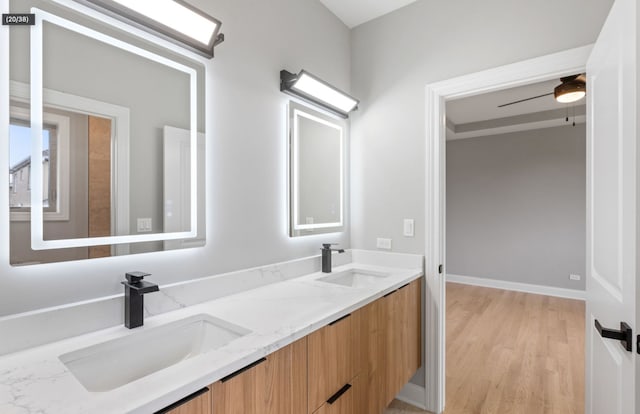 full bath featuring double vanity, wood finished floors, a sink, and a ceiling fan