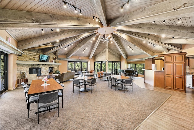 dining room featuring vaulted ceiling with beams, wooden ceiling, a healthy amount of sunlight, and a fireplace