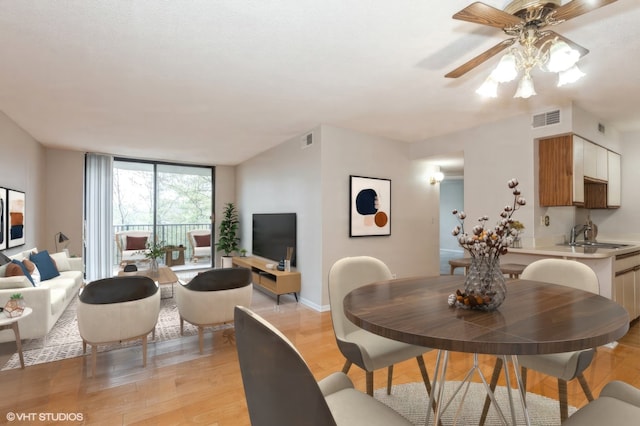 dining room with a wall of windows, baseboards, visible vents, and light wood finished floors