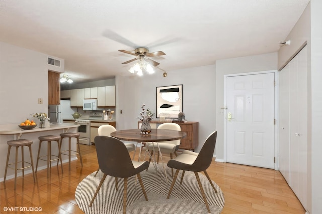 dining space featuring visible vents, a ceiling fan, and light wood-style floors