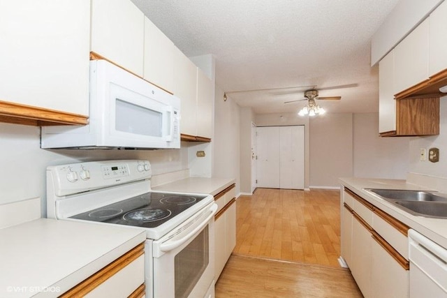 kitchen featuring light countertops, a ceiling fan, a sink, light wood-type flooring, and white appliances