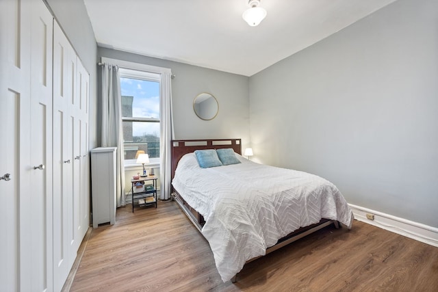 bedroom featuring a closet, wood finished floors, and baseboards