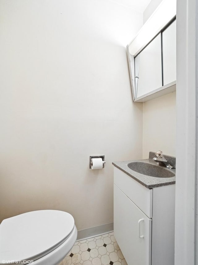 bathroom featuring baseboards, vanity, toilet, and tile patterned floors