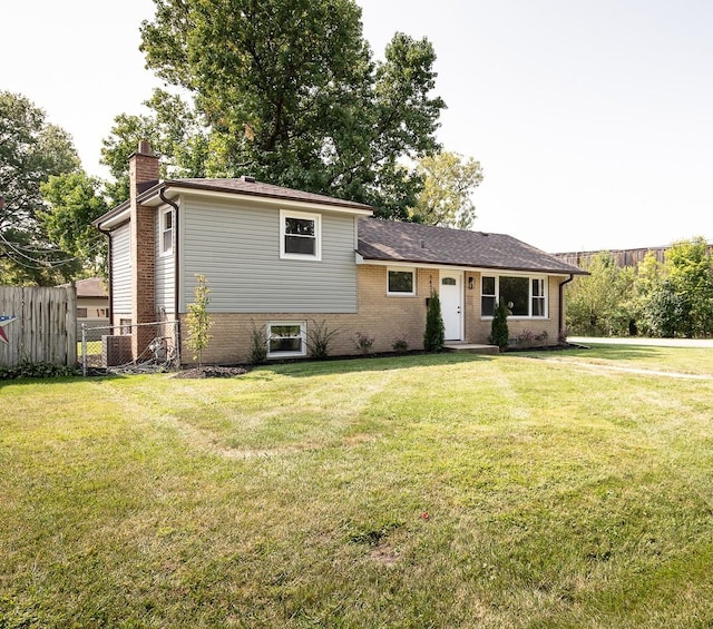 view of front facade featuring a front yard, brick siding, fence, and a chimney