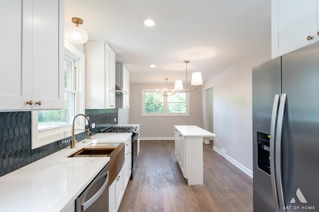 kitchen featuring a wealth of natural light, backsplash, appliances with stainless steel finishes, white cabinetry, and a sink