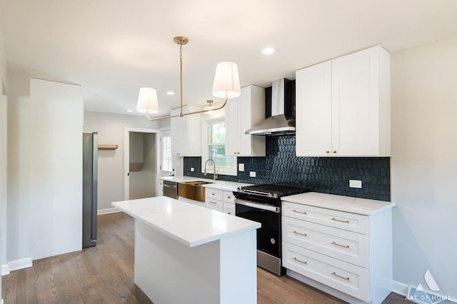 kitchen featuring tasteful backsplash, light countertops, appliances with stainless steel finishes, wall chimney range hood, and wood finished floors