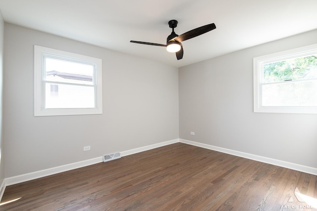 spare room featuring dark wood-style floors, baseboards, visible vents, and ceiling fan