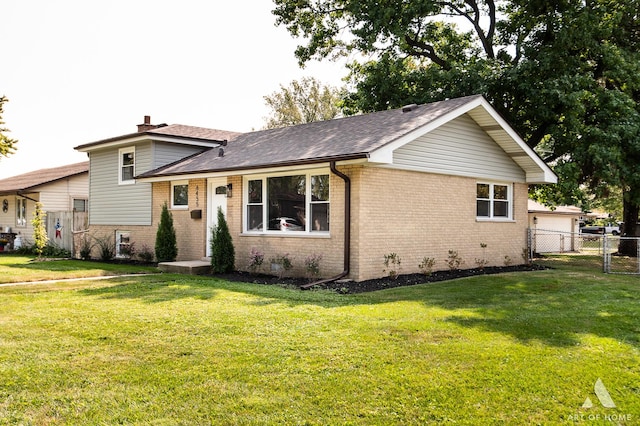 split level home with a chimney, roof with shingles, fence, a front lawn, and brick siding