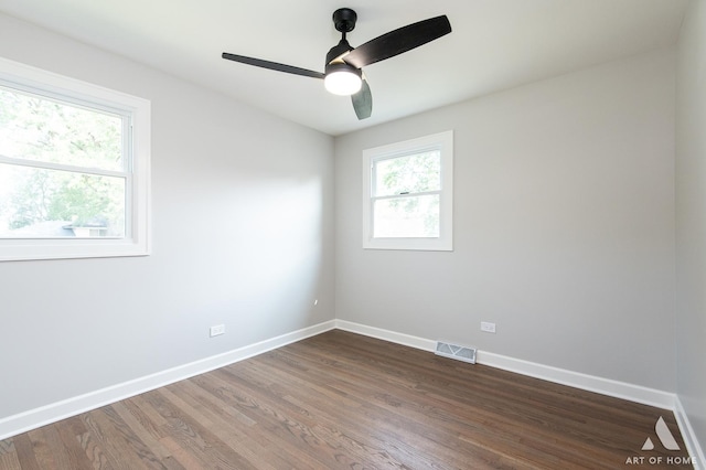 empty room featuring dark wood-style floors, visible vents, baseboards, and a ceiling fan