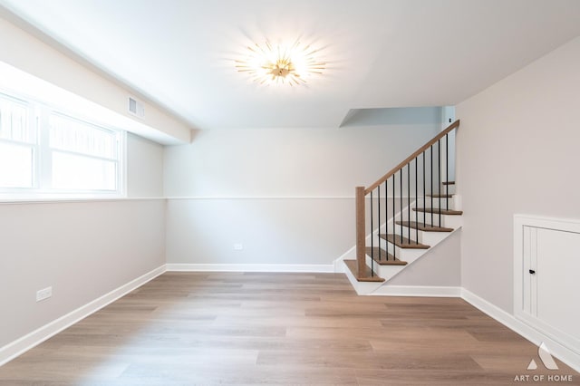 unfurnished room featuring baseboards, stairs, visible vents, and wood finished floors