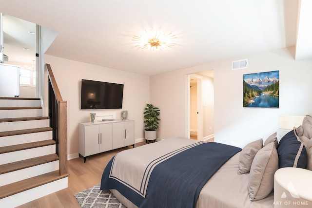 bedroom with light wood-style flooring, visible vents, and baseboards