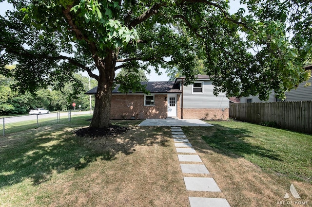 back of house featuring brick siding, a fenced backyard, and a yard