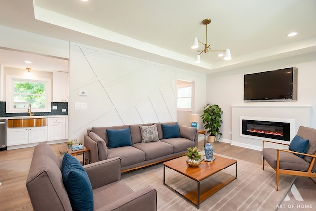 living area with a glass covered fireplace, a raised ceiling, and a wealth of natural light