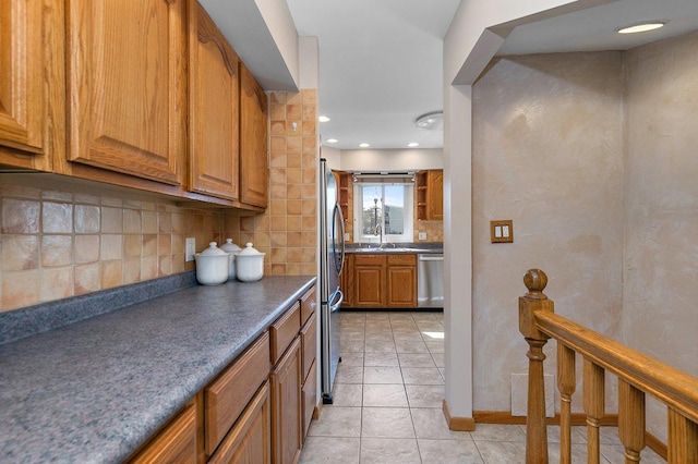 kitchen with a sink, tasteful backsplash, appliances with stainless steel finishes, and brown cabinets