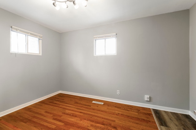 spare room with visible vents, baseboards, and wood finished floors