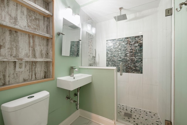 bathroom with a sink, a shower stall, toilet, and baseboards