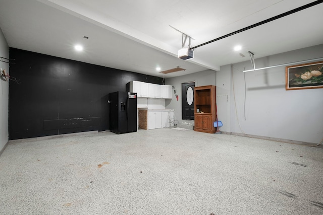 garage featuring black refrigerator with ice dispenser and a garage door opener