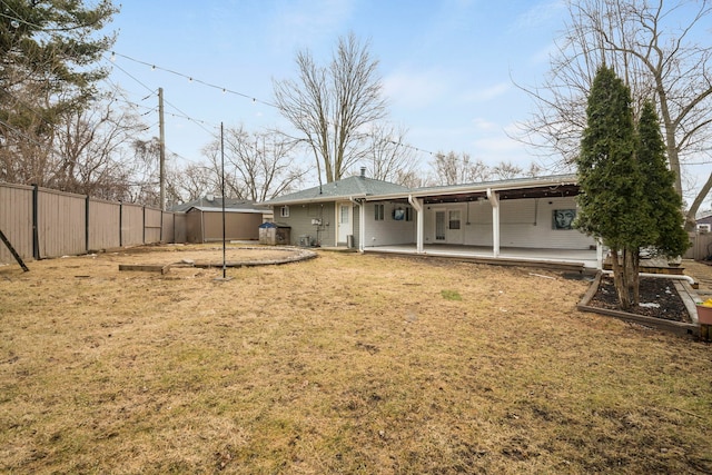 rear view of property featuring a patio, a lawn, and fence