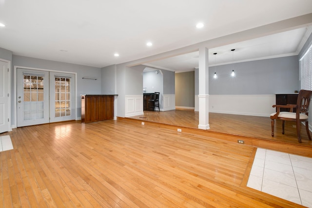 unfurnished living room featuring ornamental molding, recessed lighting, a wainscoted wall, and light wood finished floors