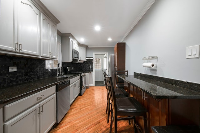 kitchen with light wood-style flooring, stainless steel appliances, crown molding, backsplash, and recessed lighting