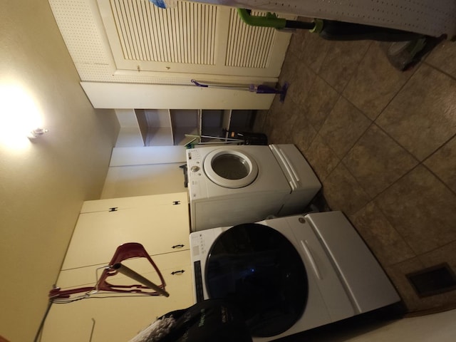 clothes washing area featuring stacked washer and clothes dryer, visible vents, and laundry area