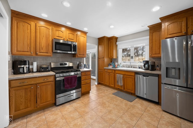 kitchen featuring appliances with stainless steel finishes, brown cabinetry, and a sink