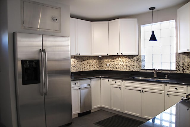 kitchen featuring tasteful backsplash, white cabinets, a sink, and stainless steel refrigerator with ice dispenser