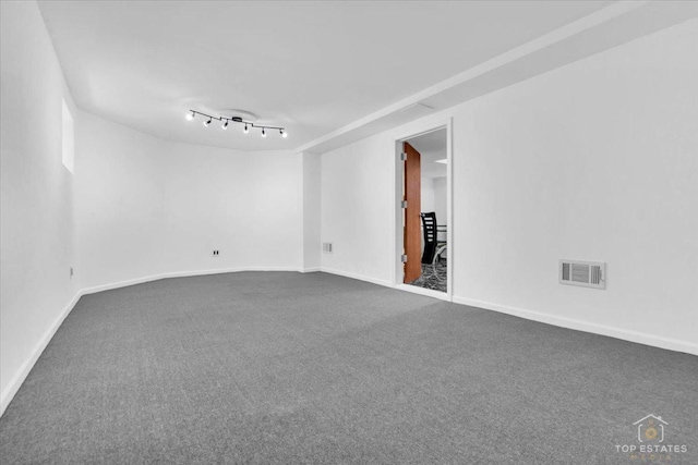 spare room featuring dark carpet, visible vents, and baseboards