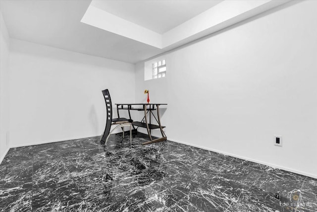 dining room featuring marble finish floor, a raised ceiling, and baseboards