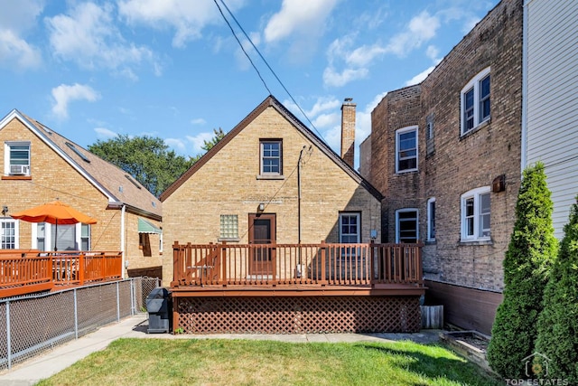 back of property with a wooden deck, a chimney, fence, a yard, and brick siding