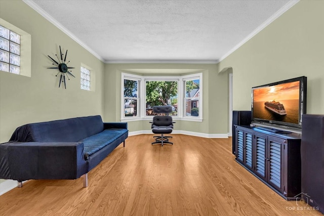 sitting room featuring a textured ceiling, baseboards, crown molding, and wood finished floors