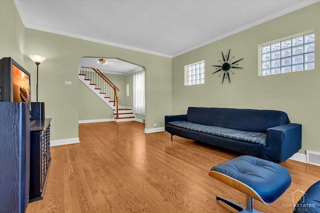 sitting room with stairway, baseboards, arched walkways, and wood finished floors