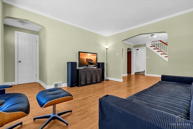 living room with arched walkways, wood finished floors, visible vents, baseboards, and ornamental molding